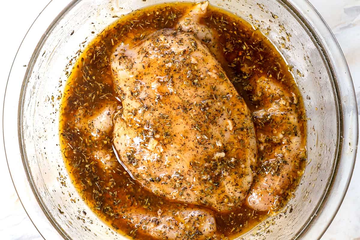 showing how to make grilled chicken by marinating the chicken in a glass bowl or freezer bag