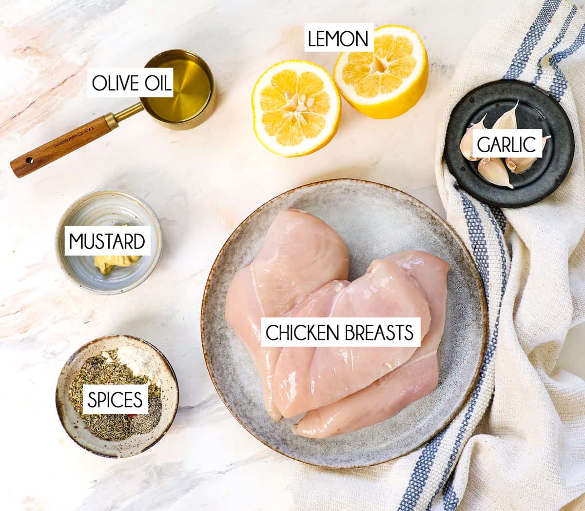 top view of grilled chicken ingredients: chicken breasts, olive oil, lemons, garlic, Dijon mustard, dried basil, dried oregano, onion powder, paprika, dried thyme, salt and pepper