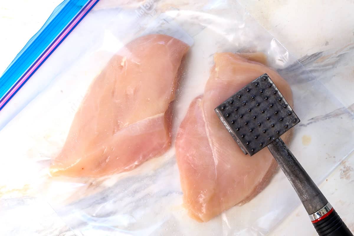 showing how to make grilled chicken by pounding the chicken breasts to an even thickness with a meat mallet