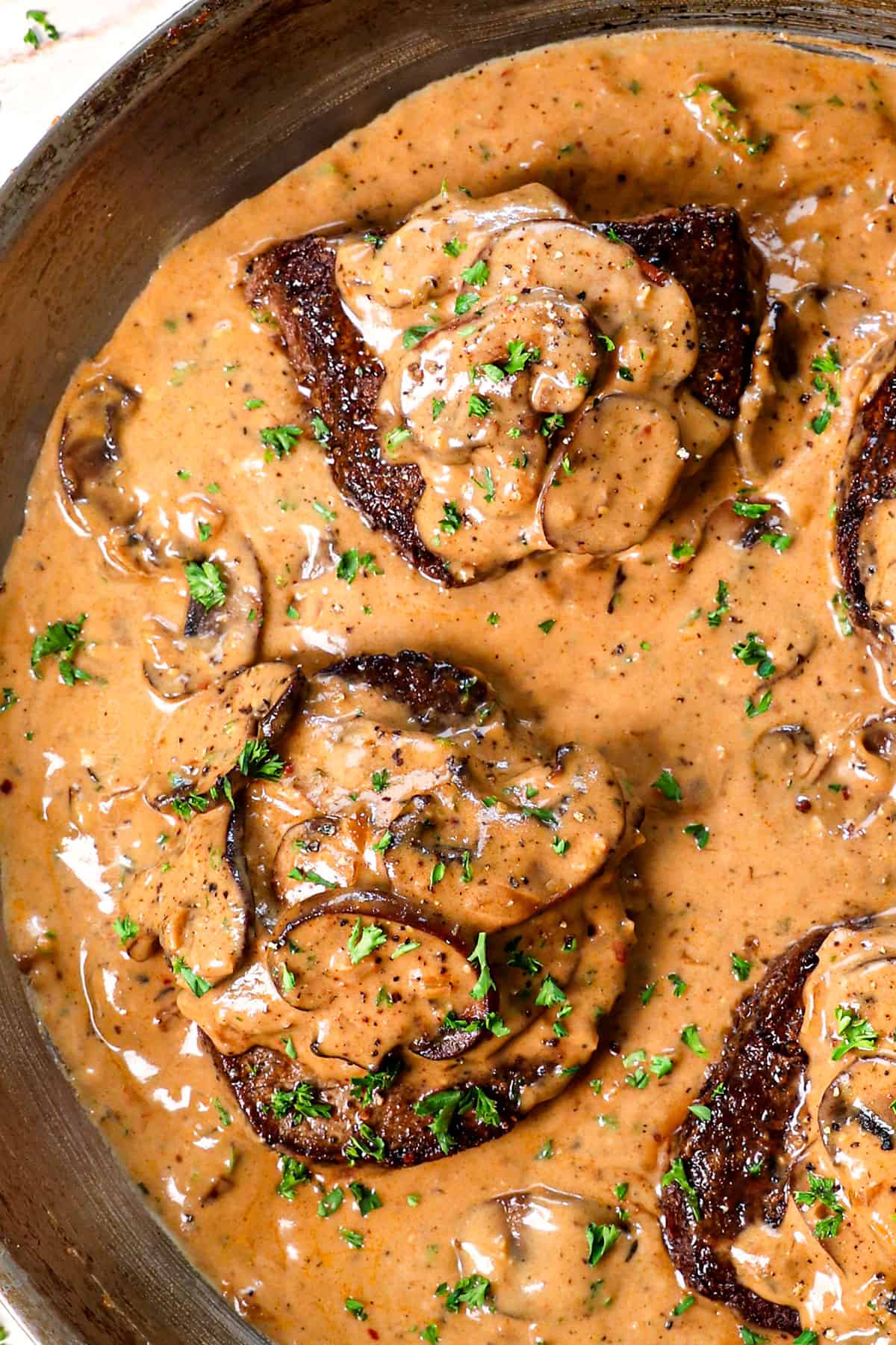 showing how to make Steak Diane by putting it in the skillet and spooning sauce over top