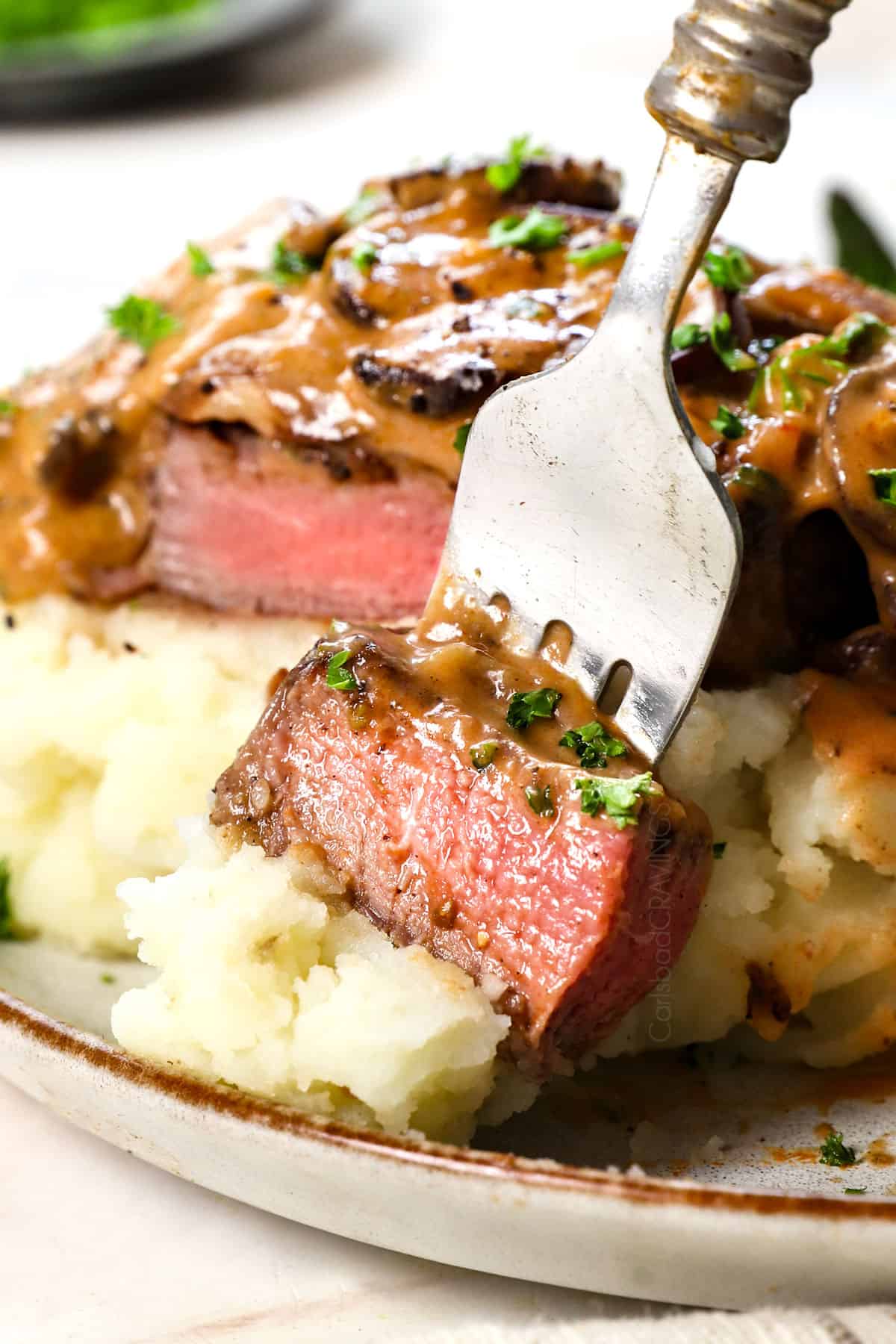 up close of a bite of steak Diane recipe showing how juicy and tender the steak is cooked to a perfect medium-rare