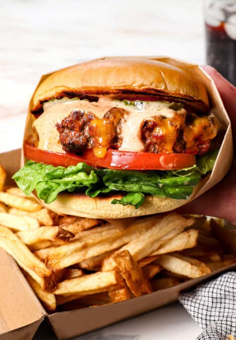 up close of holding a burger with burger sauce dripping down