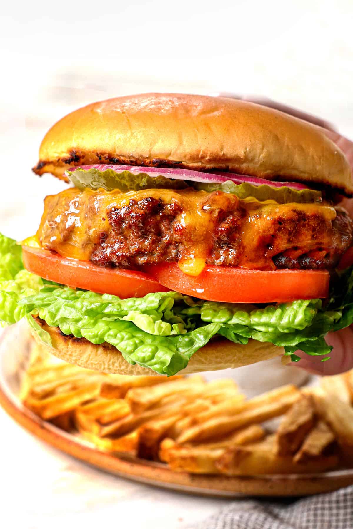 up close of hand holding a cheeseburger showing how juicy and cheesy it is