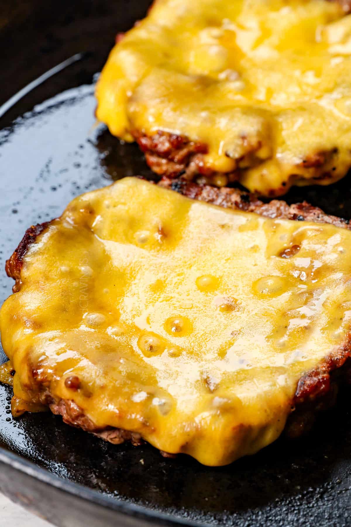 showing how to make cheeseburgers by cooking both sides, then adding the cheese the last minute of cooking