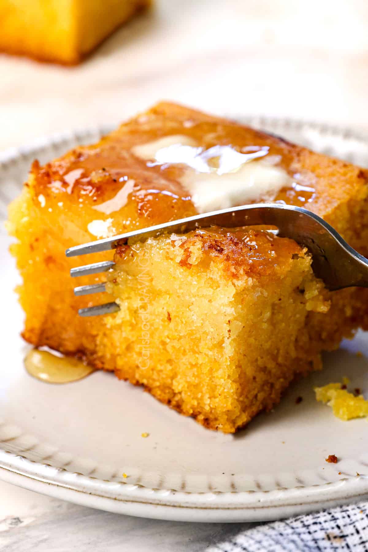 up close of a fork taking a bite out of homemade cornbread, showing how moist it is