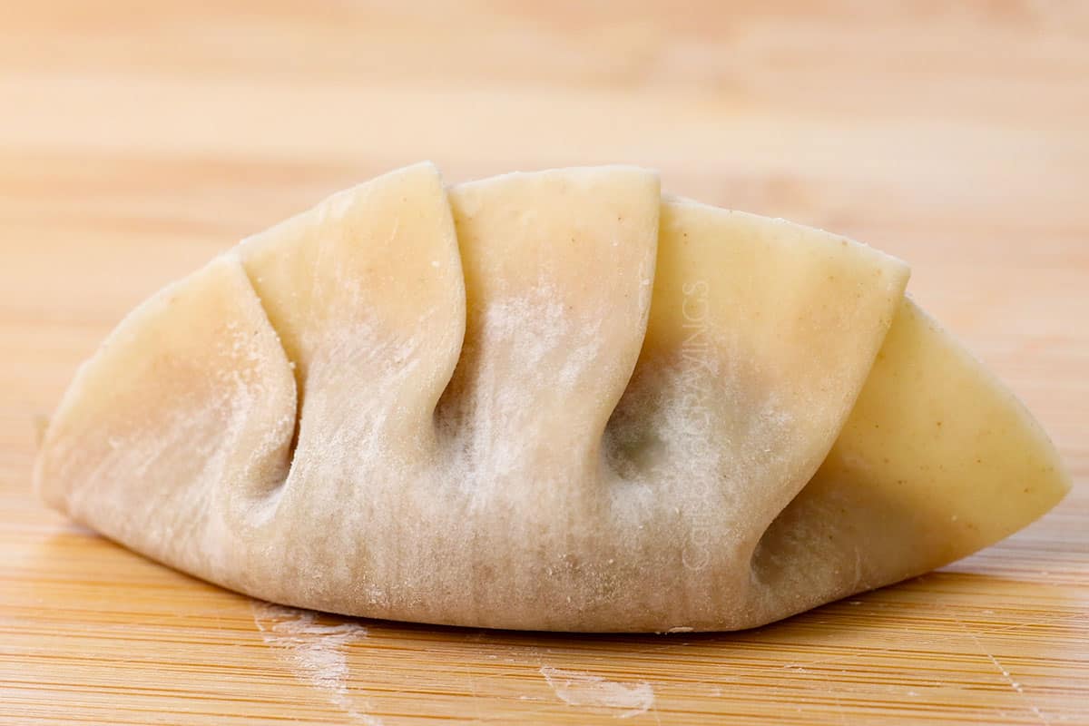 showing how to make gyoza dumplings by showing a folded, completed dumpling showing what it looks like