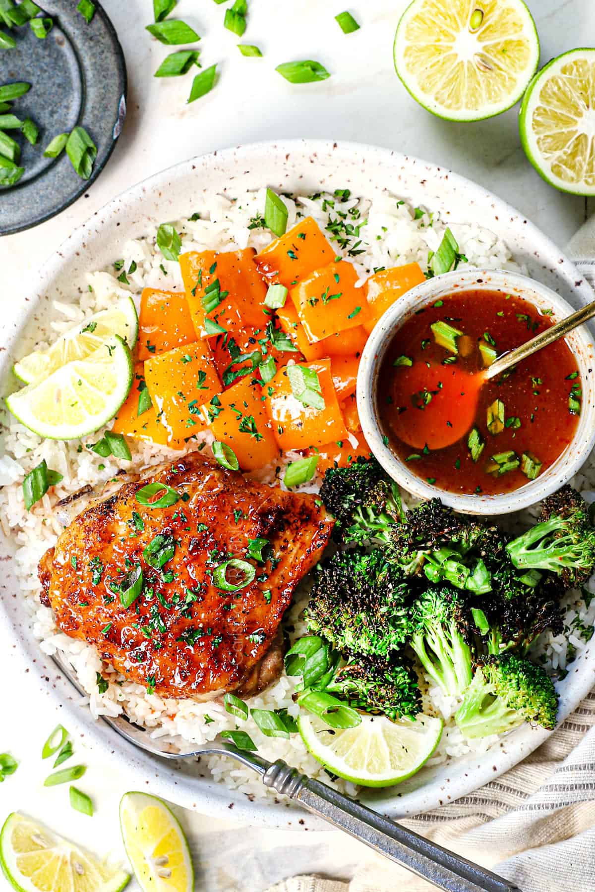 showing how to serve chicken thigh air fryer on a plate with air fried vegetables, rice, and freshly squeezed lime