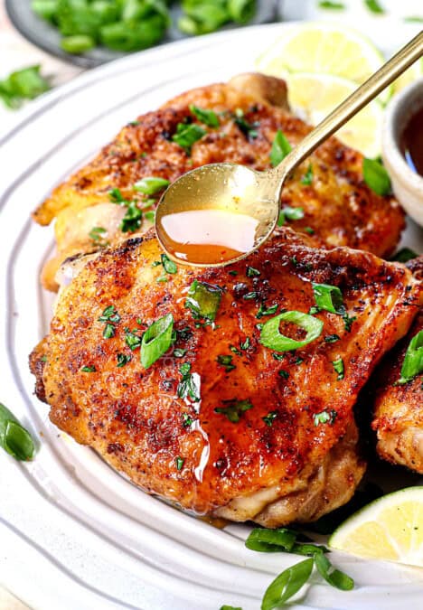 chicken thighs in air fryer with a glaze being drizzled on