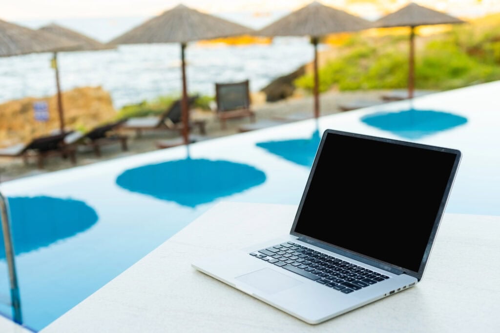 Laptop on the table on the beach for the article 10 Best Ways To Use ChatGPT To Make Money