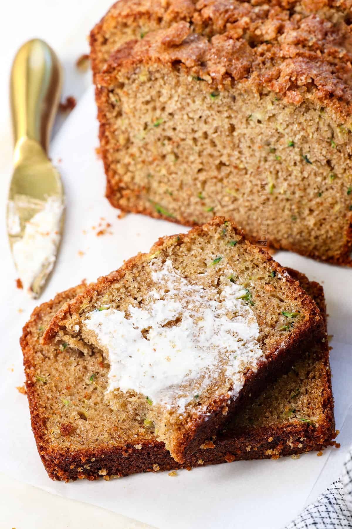 showing how to serve zucchini bread by slathering it with butter