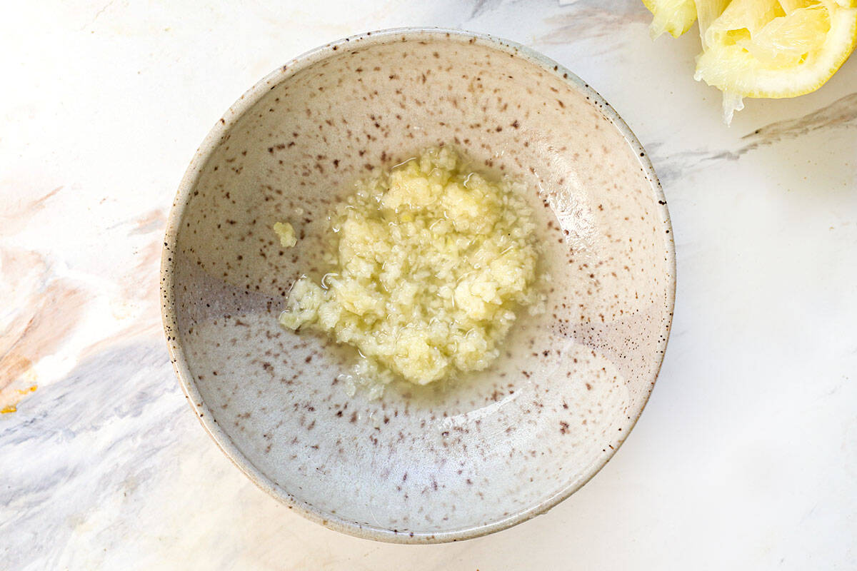 top view showing how to make garlic aioli by combining the the lemon juice and garlic in a bowl