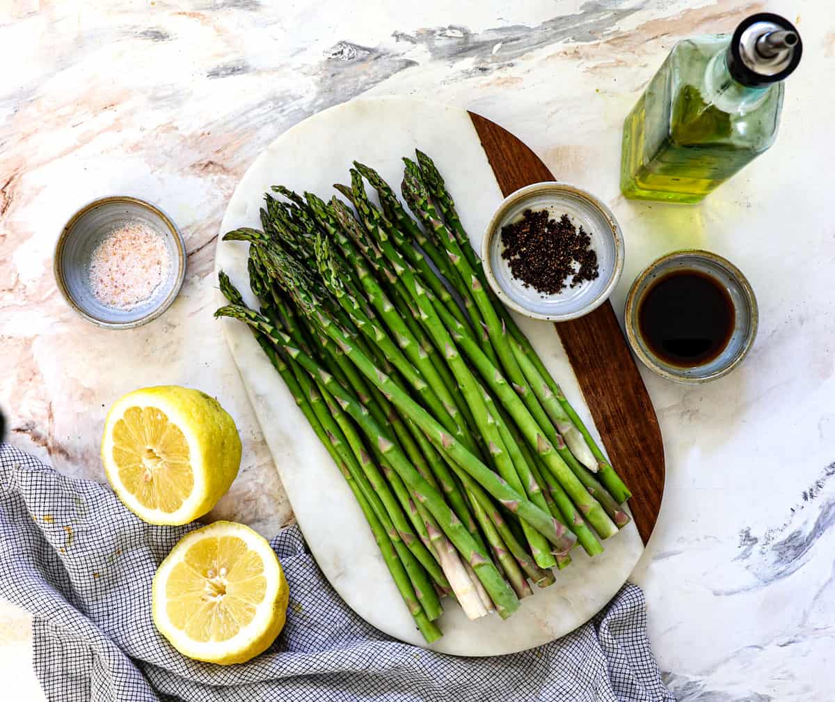 top view of grilled asparagus ingredients: asparagus, olive oil, lemon, lemon pepper, salt, pepper