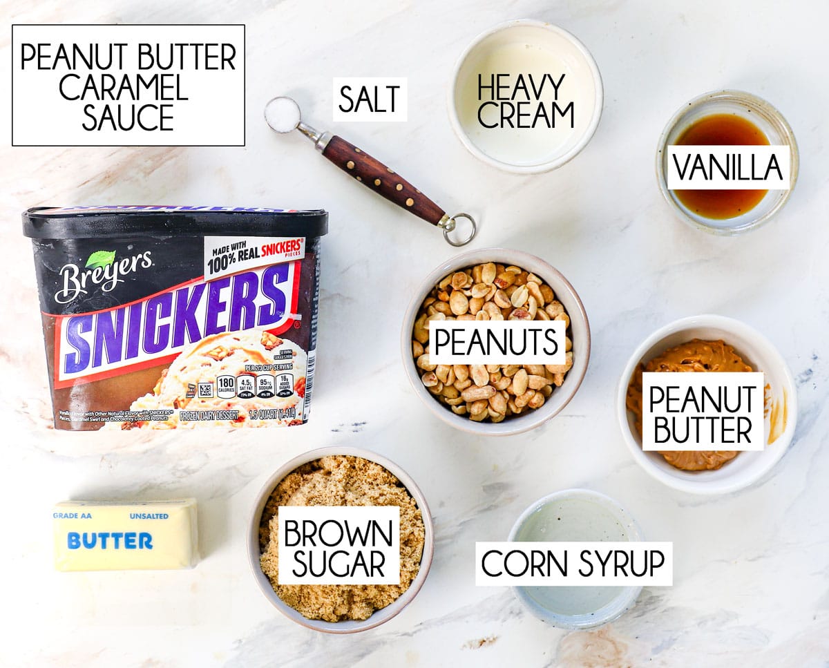 top view of ice cream cake ingredients, Snicker's ice cream, cake ingredients, peanut butter, butter, chopped peanuts, heavy cream, vanilla, corn syrup, salt