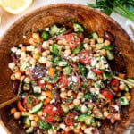 top view of tossing garbanzo bean salad in a bowl