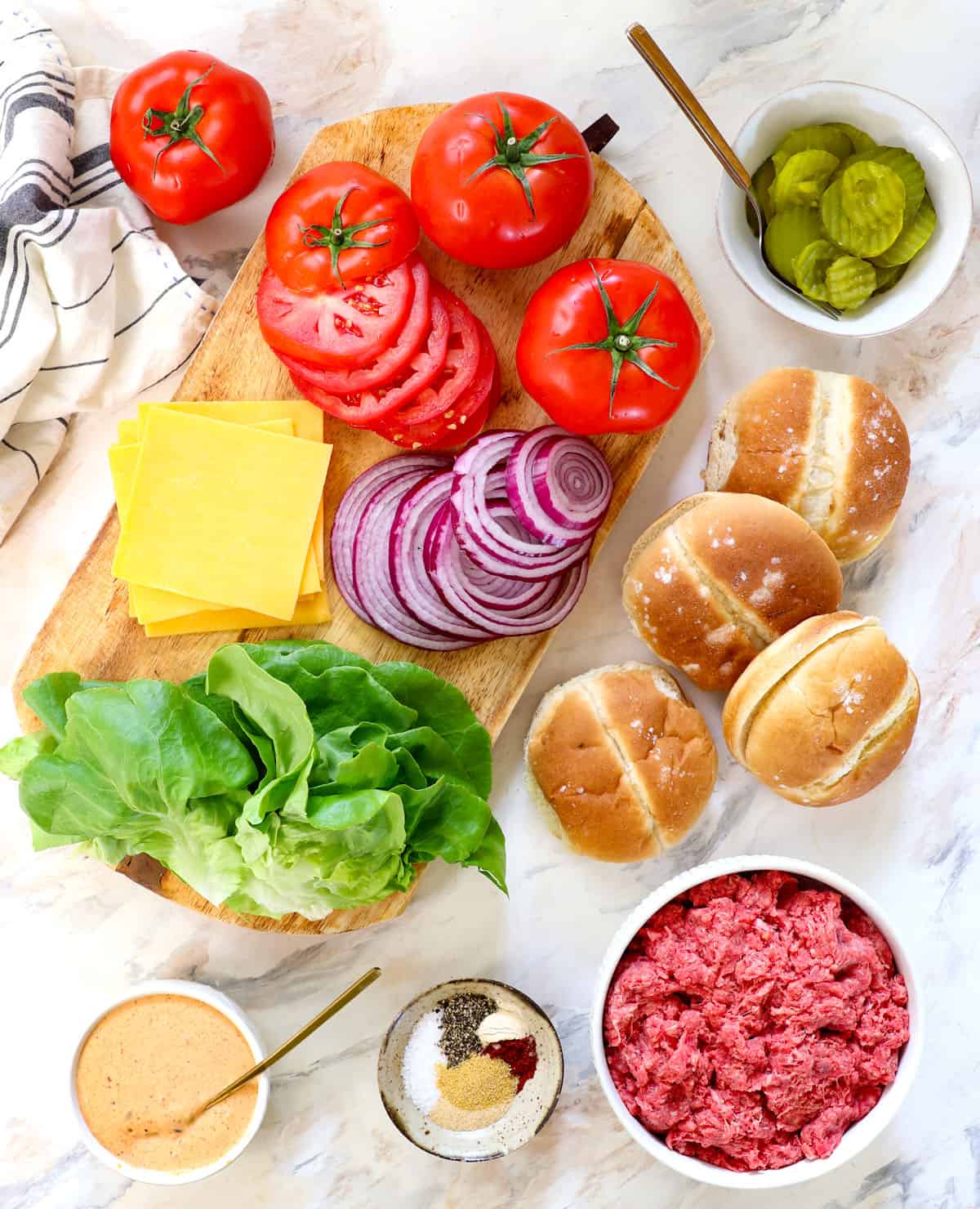 top view of smash burger Ingredients: ground beef 80/20, brioche buns, spices, smash burger sauce, tomatoes, red onion, cheese, lettuce and pickles