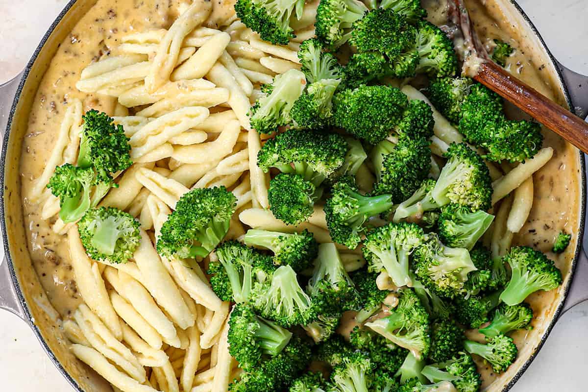 showing how to make cavatelli by stirring in the pasta and broccoli