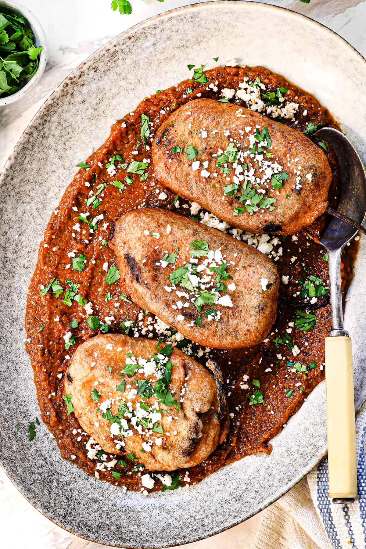 chile relleno recipe being served on a platter on top of salsa ranchera