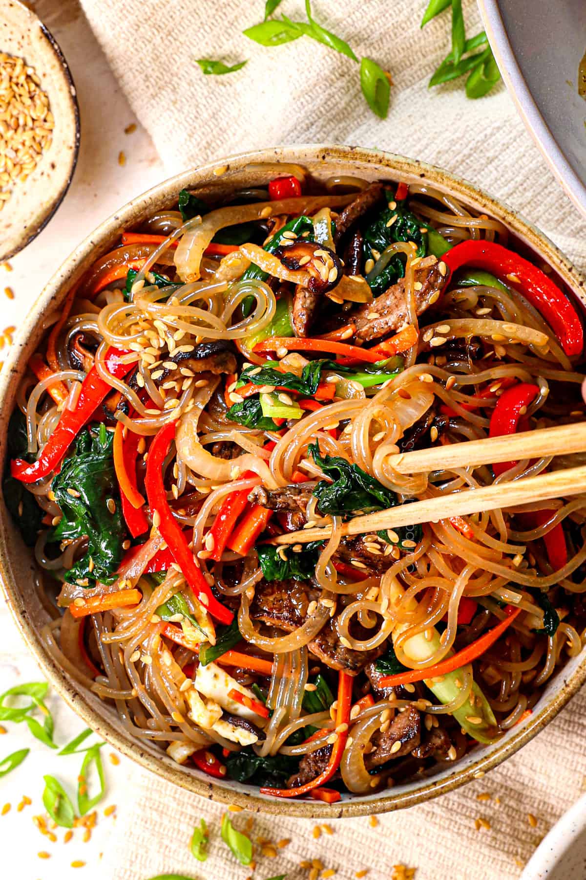 japchae noodles in a bowl being eaten with chopsticks