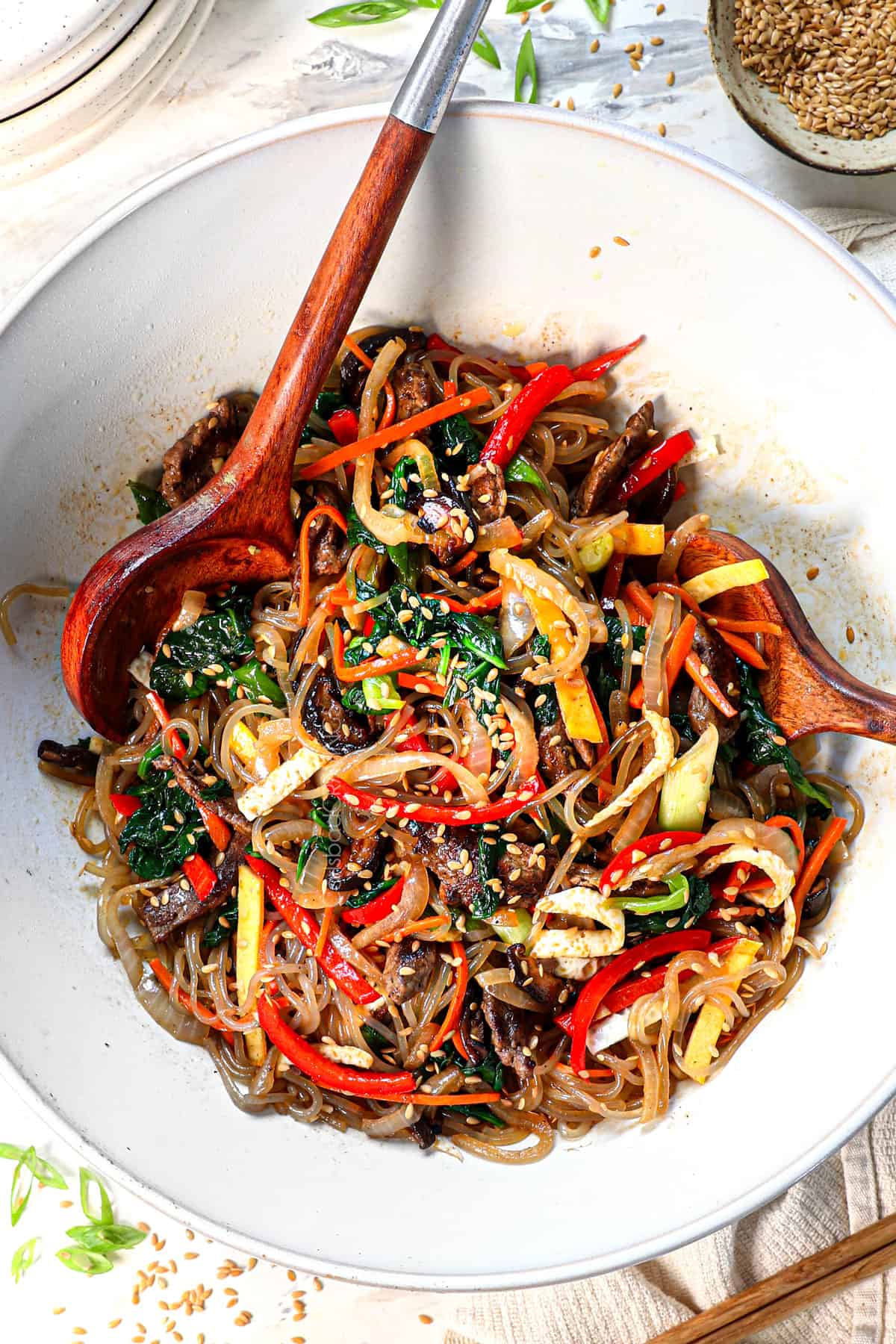 showing how to make Japchae by garnishing with sesame seeds