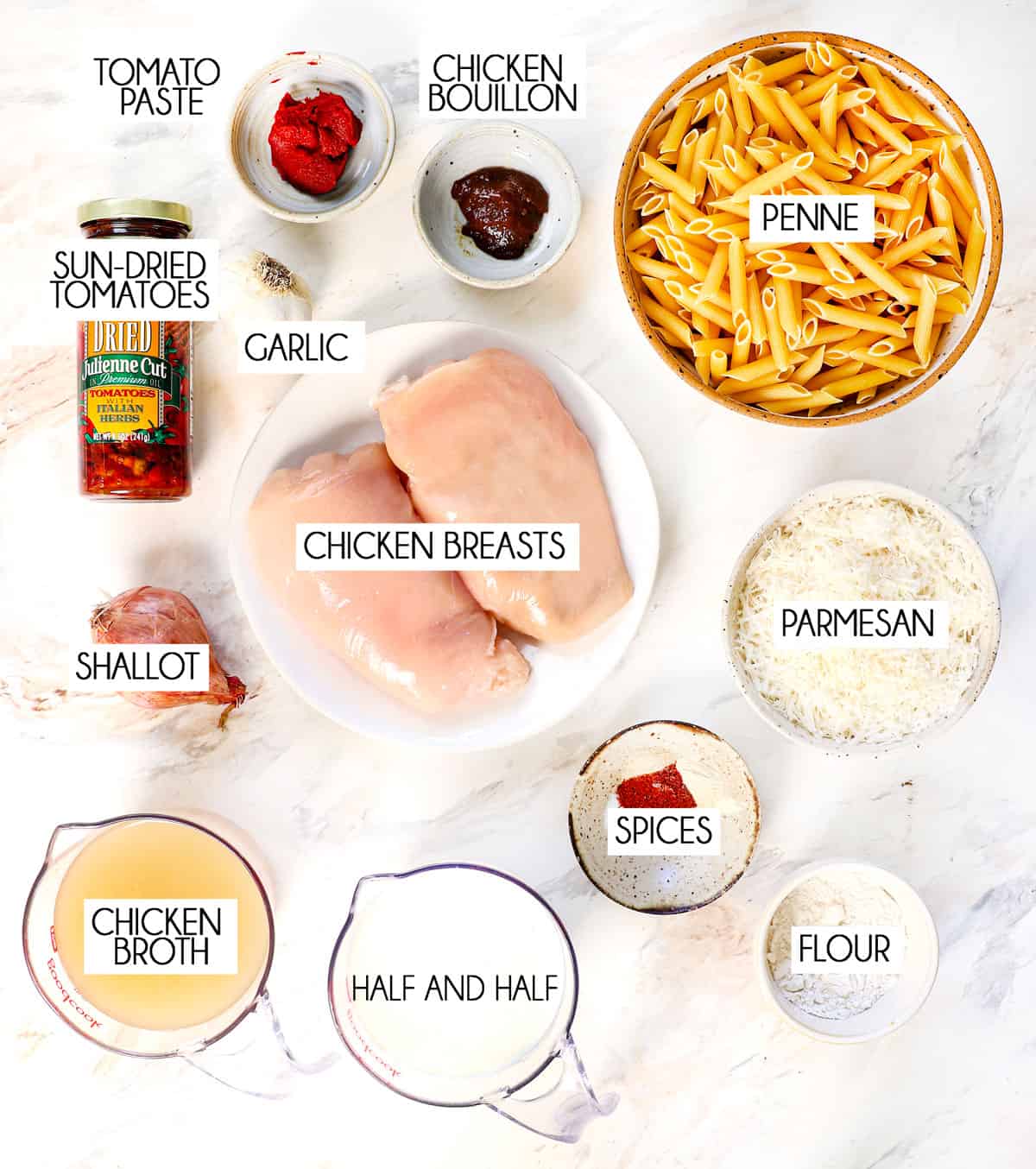 top view of marry me chicken ingredients: penne pasta, chicken breasts, sun-dried tomatoes, half and half, tomato paste, Parmesan cheese, garlic, shallot, spices, chicken broth and flour