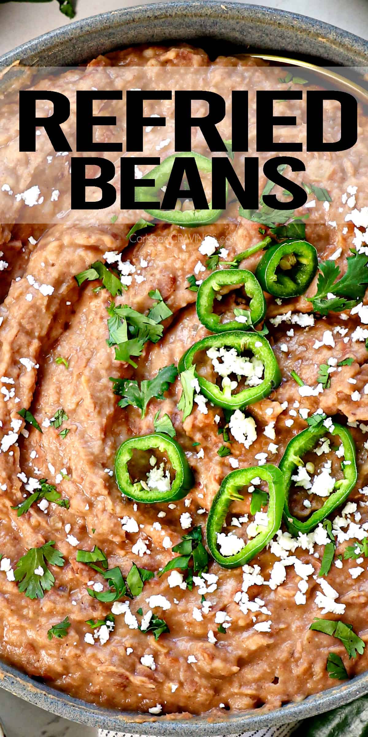 top view of refried beans in a bowl topped with jalapenos and cotija cheese