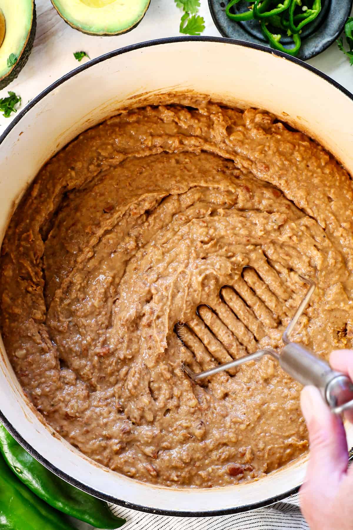 showing how to make refried beans by adding the pureed beans to the smashed beans and combining
