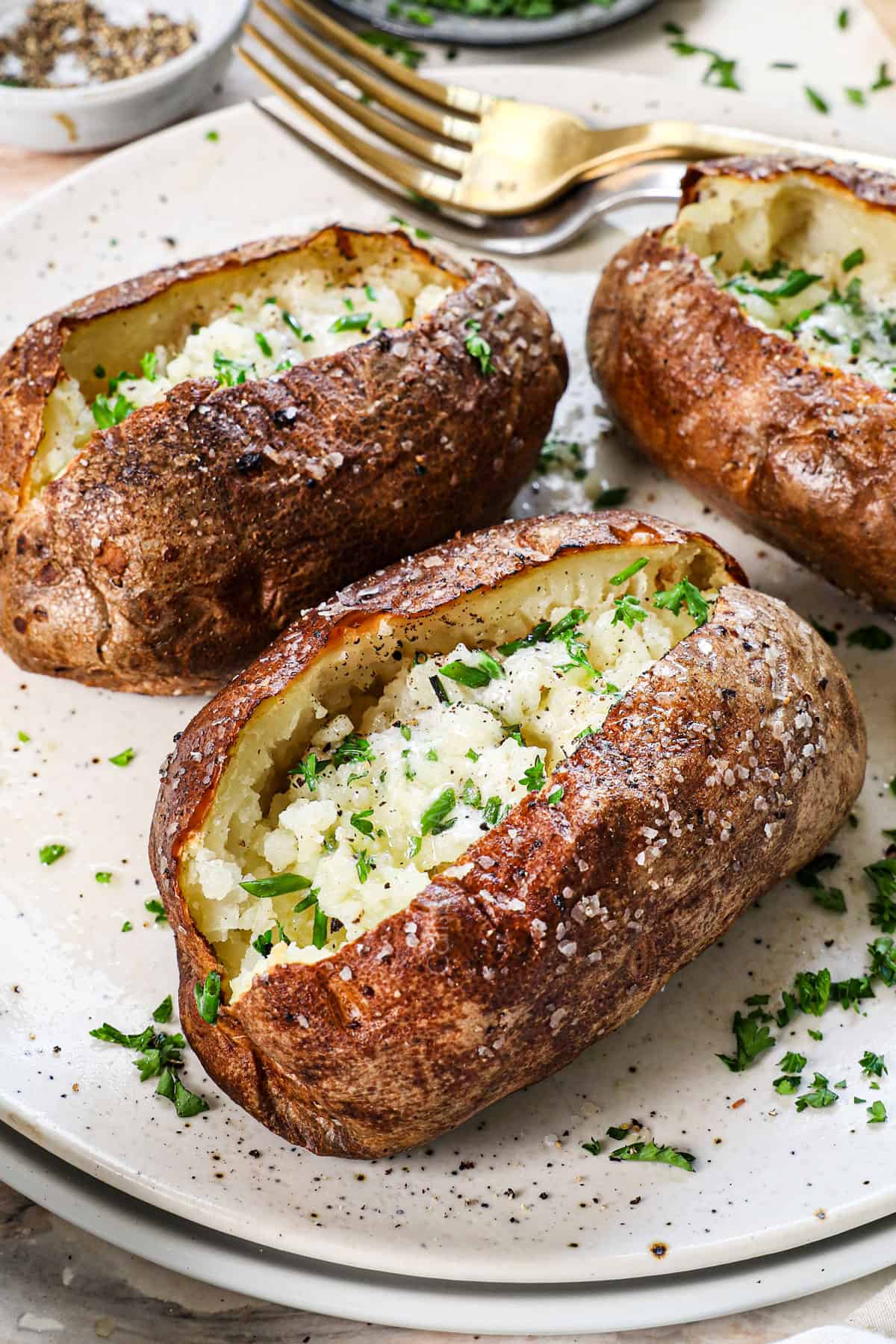showing how to make baked potato in the air fryer by serving with butter and chives
