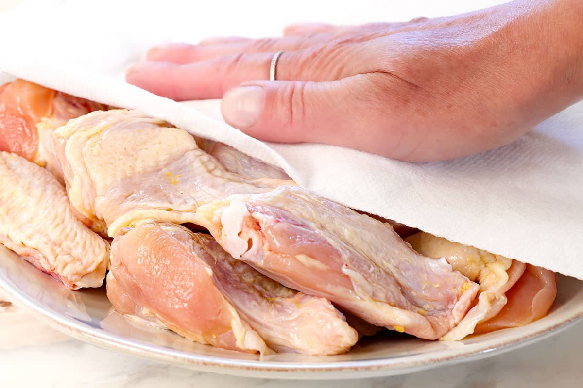 showing how to air fry chicken wings by patting the wings dry with paper towels
