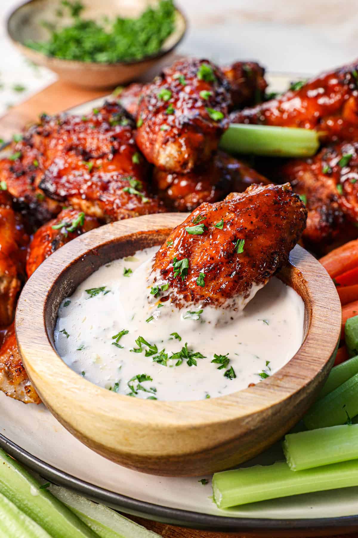showing how to air fry chicken wings by dipping in a sauce