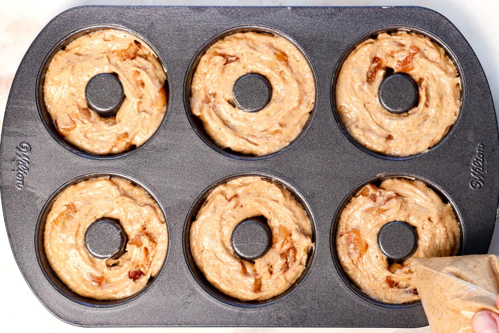 showing how to make Apple Cider Donuts by piping the batter into the pans to bake