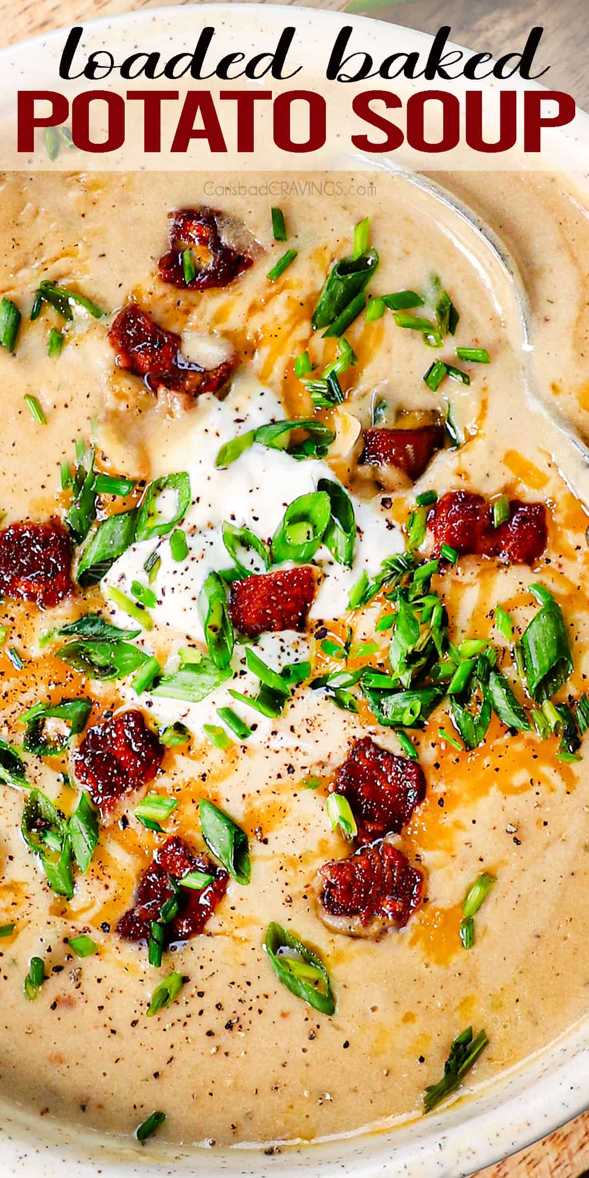top view of baked potato soup in a serving bowl topped with sour cream, bacon, cheese, and green onions
