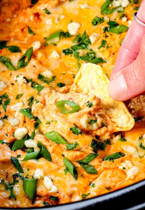 crockpot buffalo chicken dip being scooped up by a tortilla chip showing how creamy it is