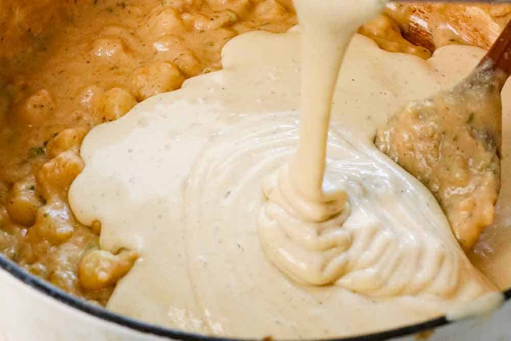 Showing how to make baked potato soup by adding pureed soup to the pot