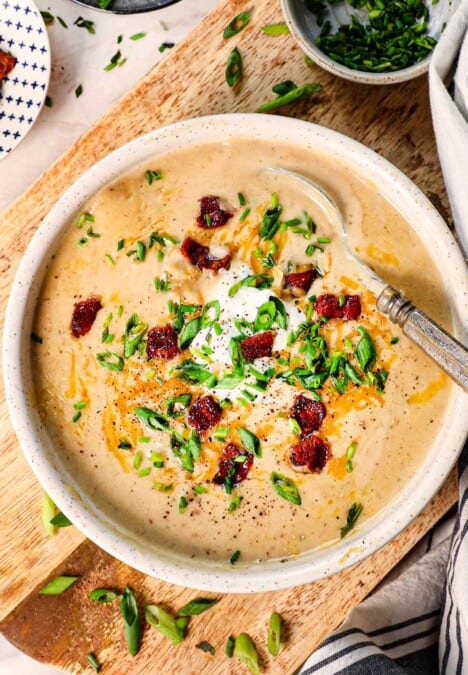 top view of loaded baked potato soup recipe in a bowl with sour cream, bacon, and green onions