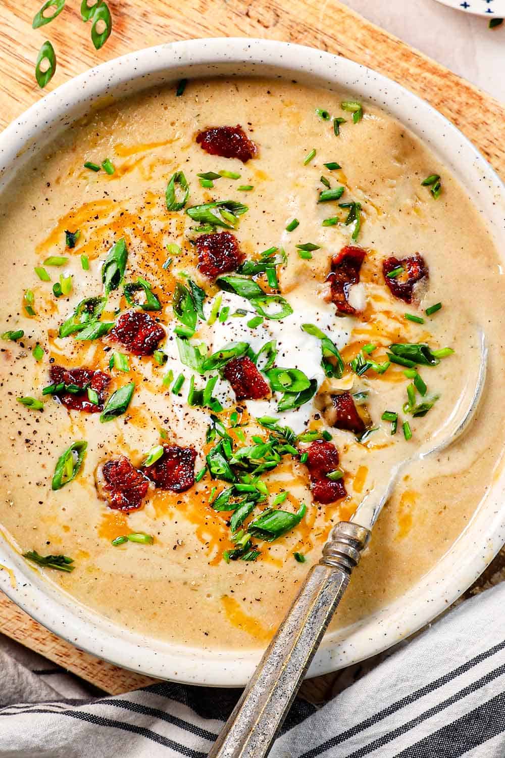 top view of loaded baked potato soup recipe in a bowl with sour cream, bacon, and green onions