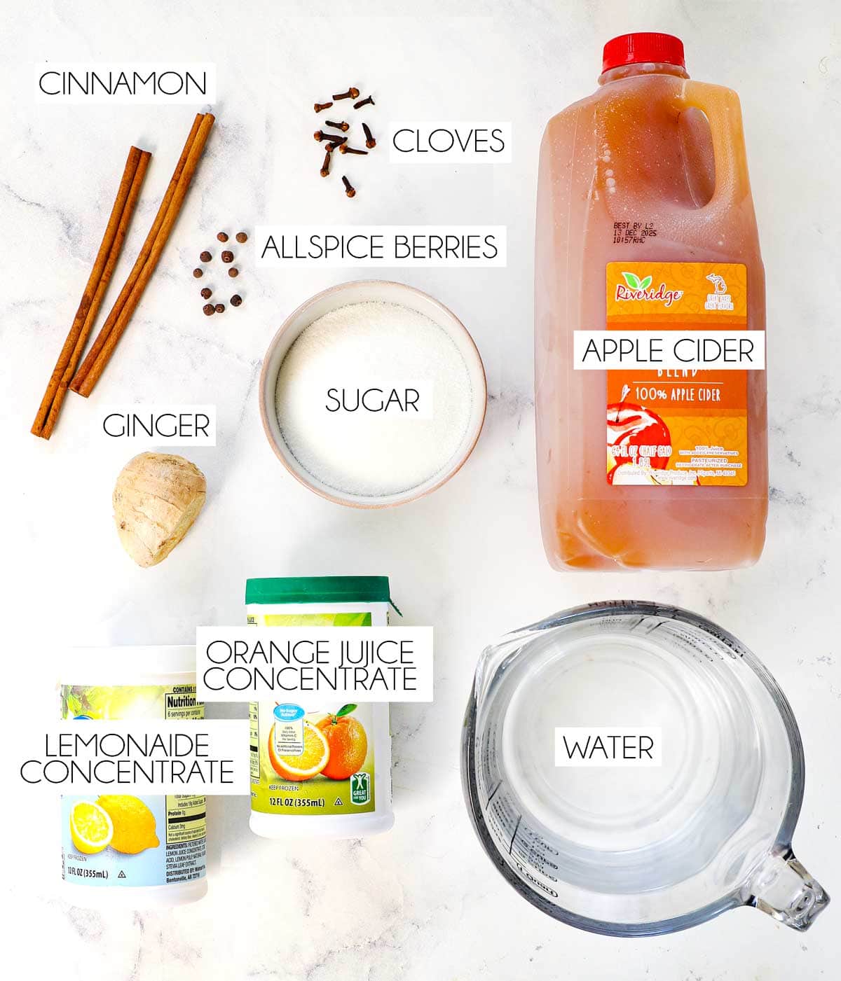 top view of wassail ingredients: apple cider, orange juice concentrate, lemonade concentrate, water, sugar, cinnamon, allspice berries, ginger, cloves
