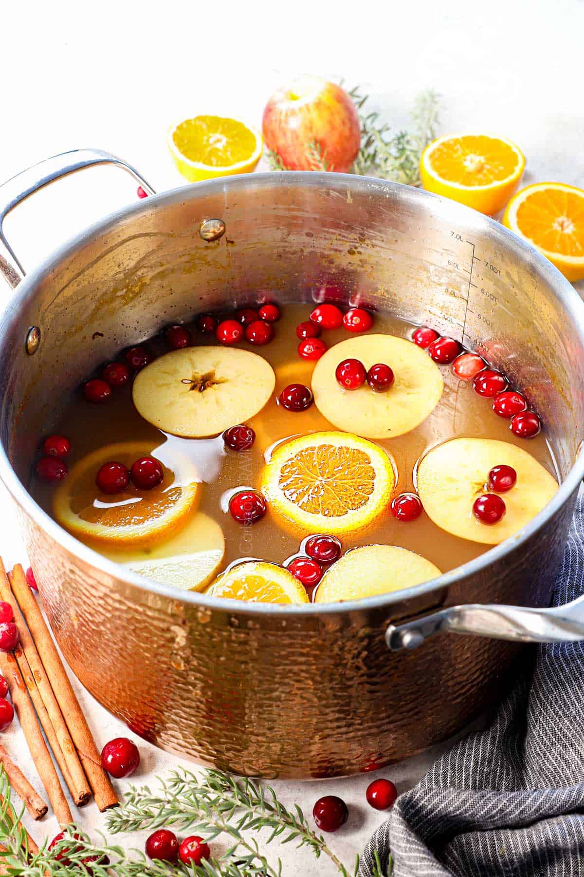 a pot of wassail drink garnished with orange and apple slices