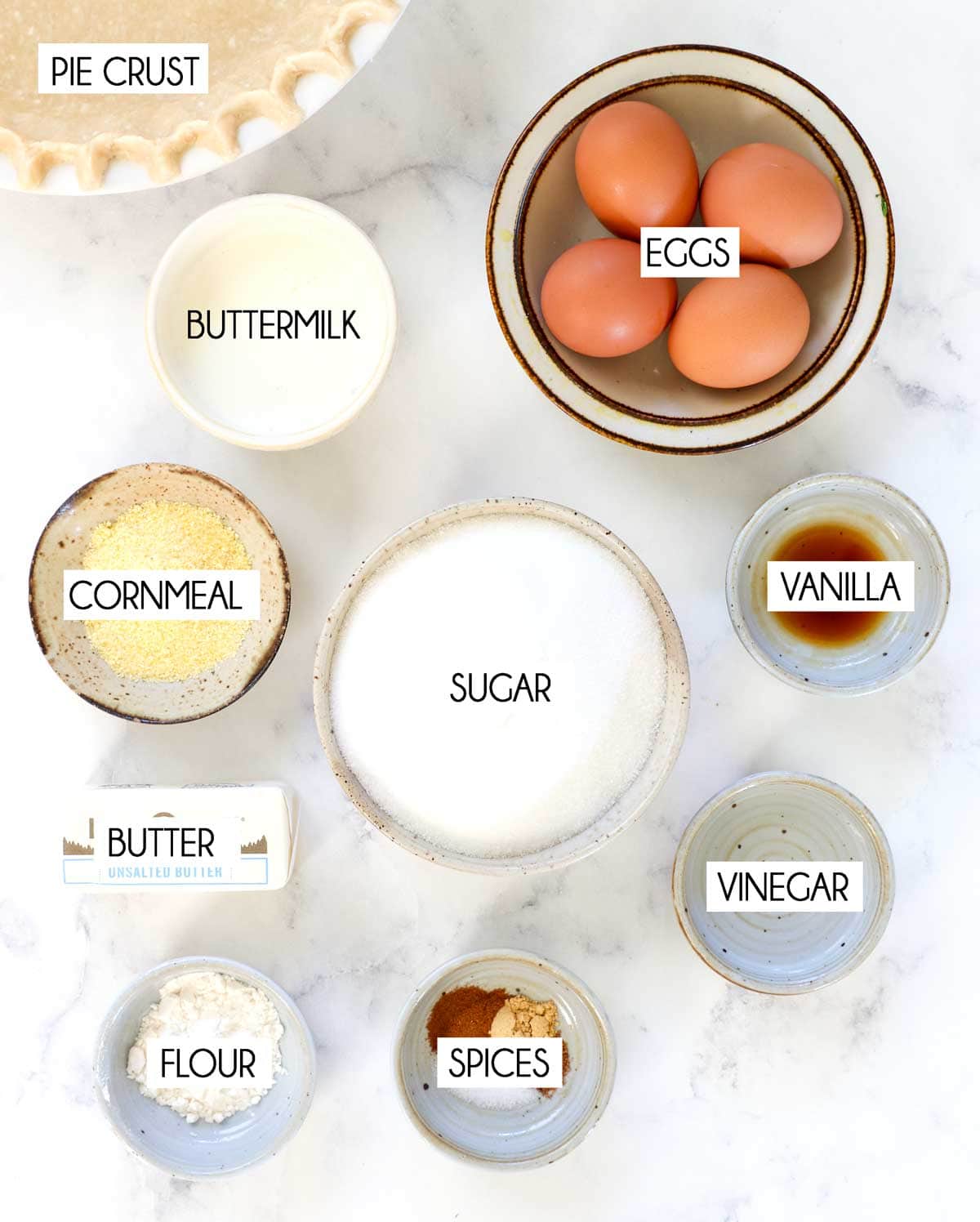 top view of chess pie ingredients: eggs, sugar, buttermilk, butter, white vinegar, flour, cornmeal, ground cinnamon