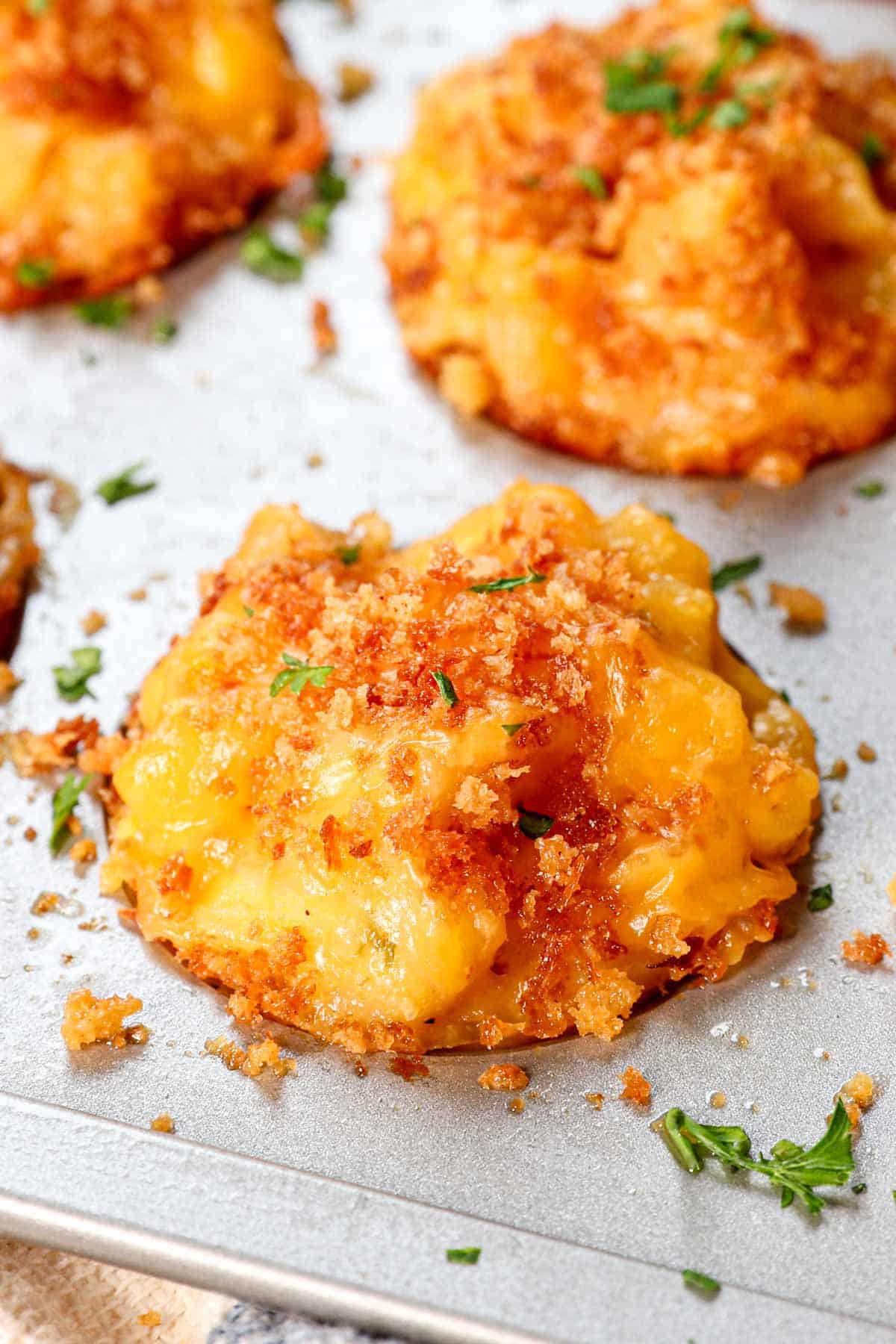 up close of mac and cheese bite in a muffin tin showing the golden top
