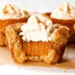 up close of a mini pumpkin pie with a bite taken out of it showing the creamy, silking pumpkin pie filling