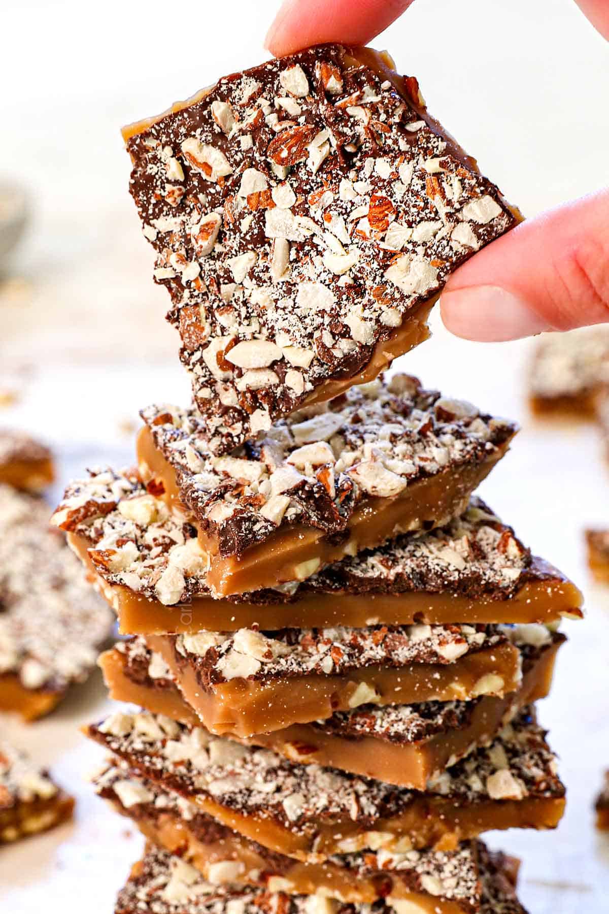 holding a pice of almond roca from a stack showing the size and texture and layers