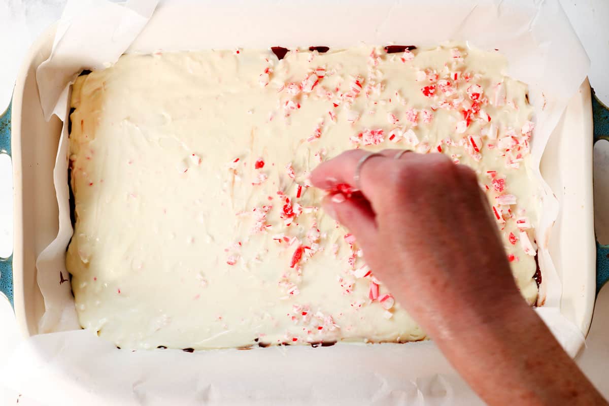 showing how to make peppermint bark by spreading melted white chocolate over the chocolate layer and sprinkling with crushed candy canes