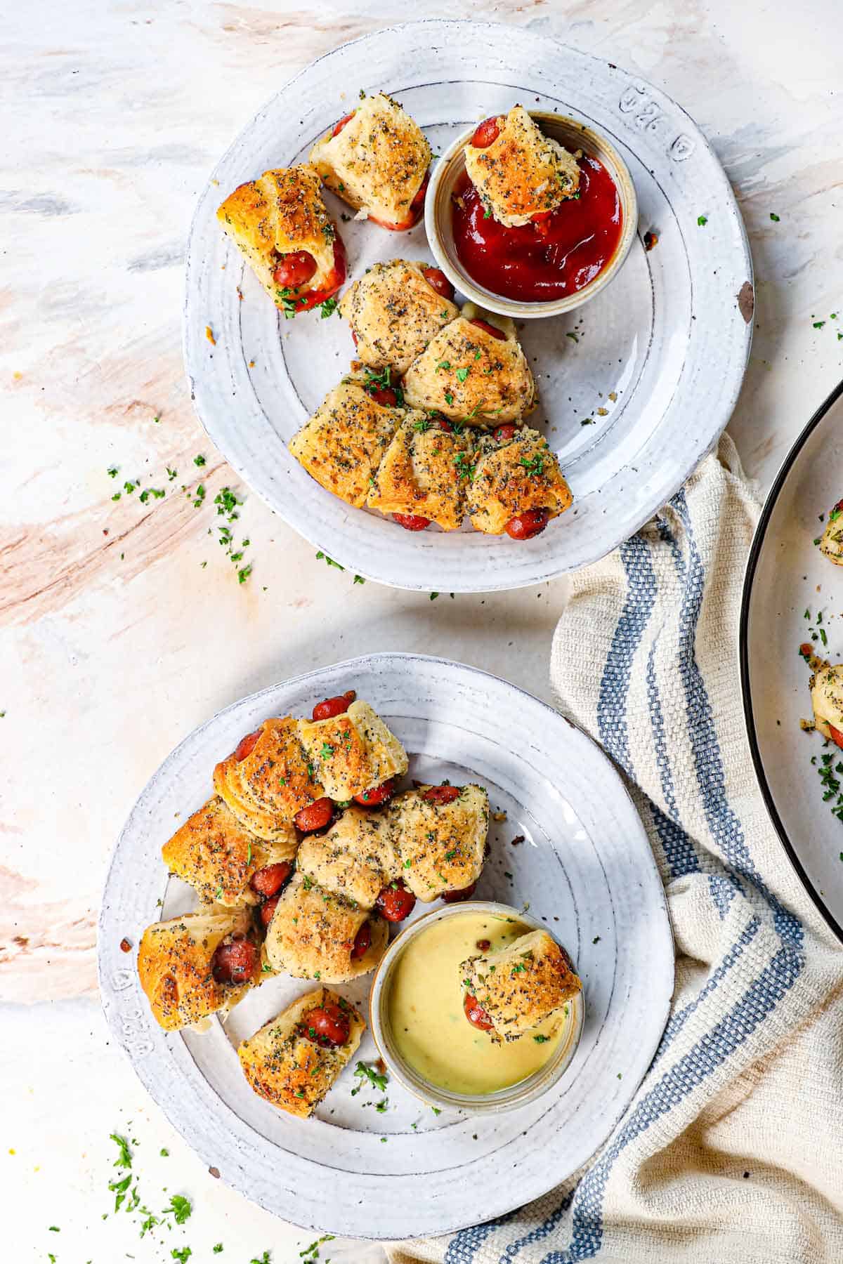 showing how to serve Pillsbury pigs in a blanket on plates with dipping sauces of ketchup and mustard