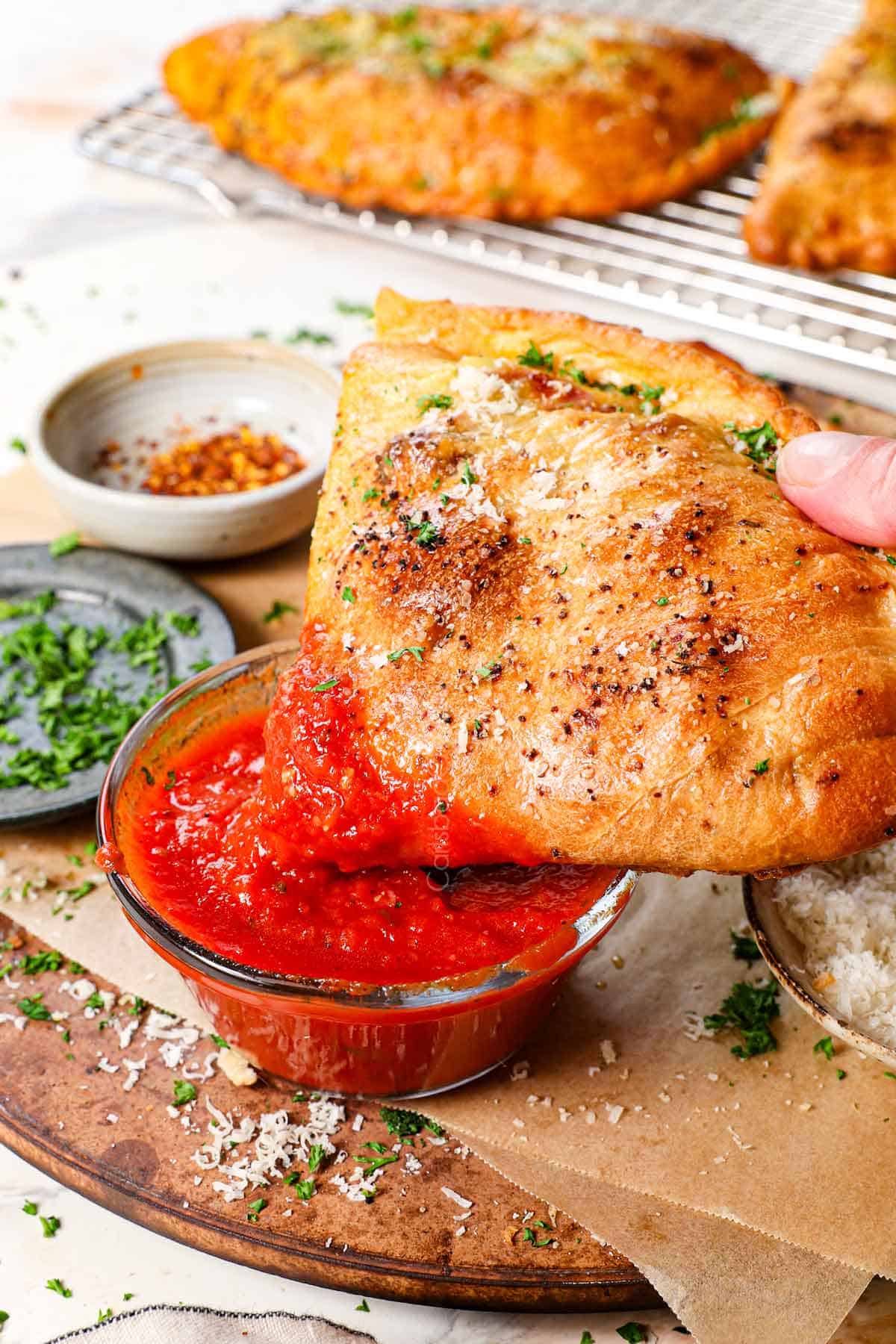 showing how to serve calzone recipes by dipping the calzone in marinara sauce