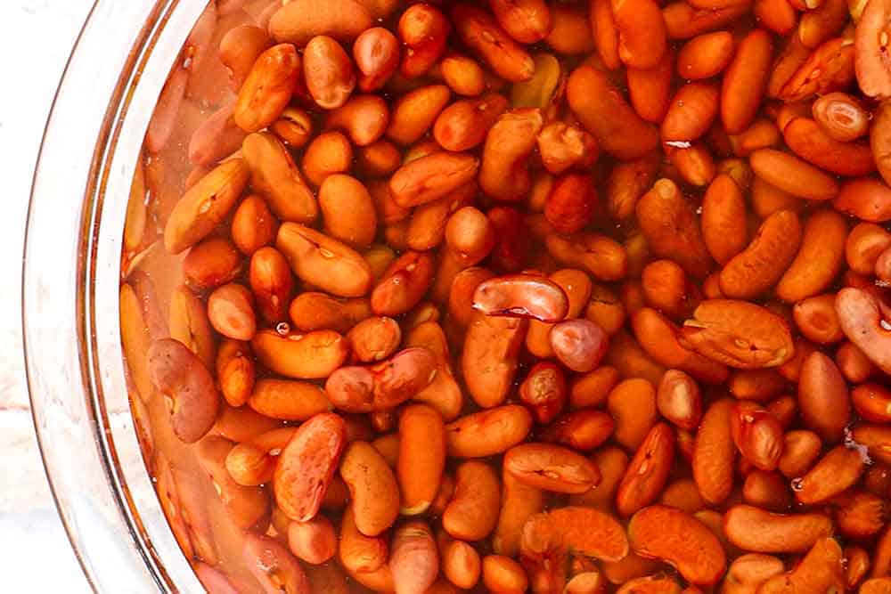 showing how to make red beans and rice by soaking the beans in a bowl of water
