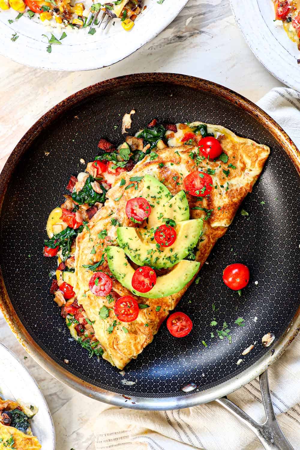 showing how to make an omelette by folding the omelette over the filling in the pan